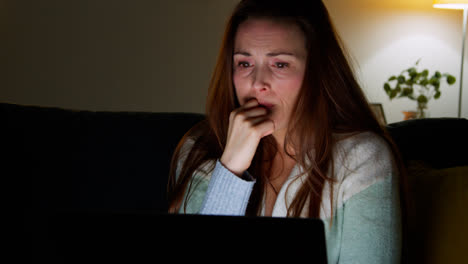 Close-Up-Of-Anxious-Woman-Sitting-On-Sofa-At-Home-At-Night-Looking-At-Laptop-Concerned-About-Social-Media-Or-Bad-News-8